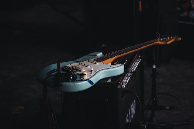 Guitarra azul em cima de caixa amplificadora.